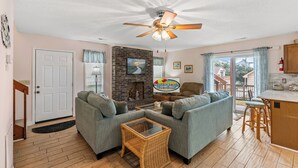 A cozy living room with two sofas, a coffee table, a fireplace, and a ceiling fan. - Pet Friendly Newly Updated Home + Free Attraction Tickets! (North Myrtle Beach)