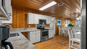 A kitchen with wooden walls, white cabinets, a stainless steel oven, and a microwave.