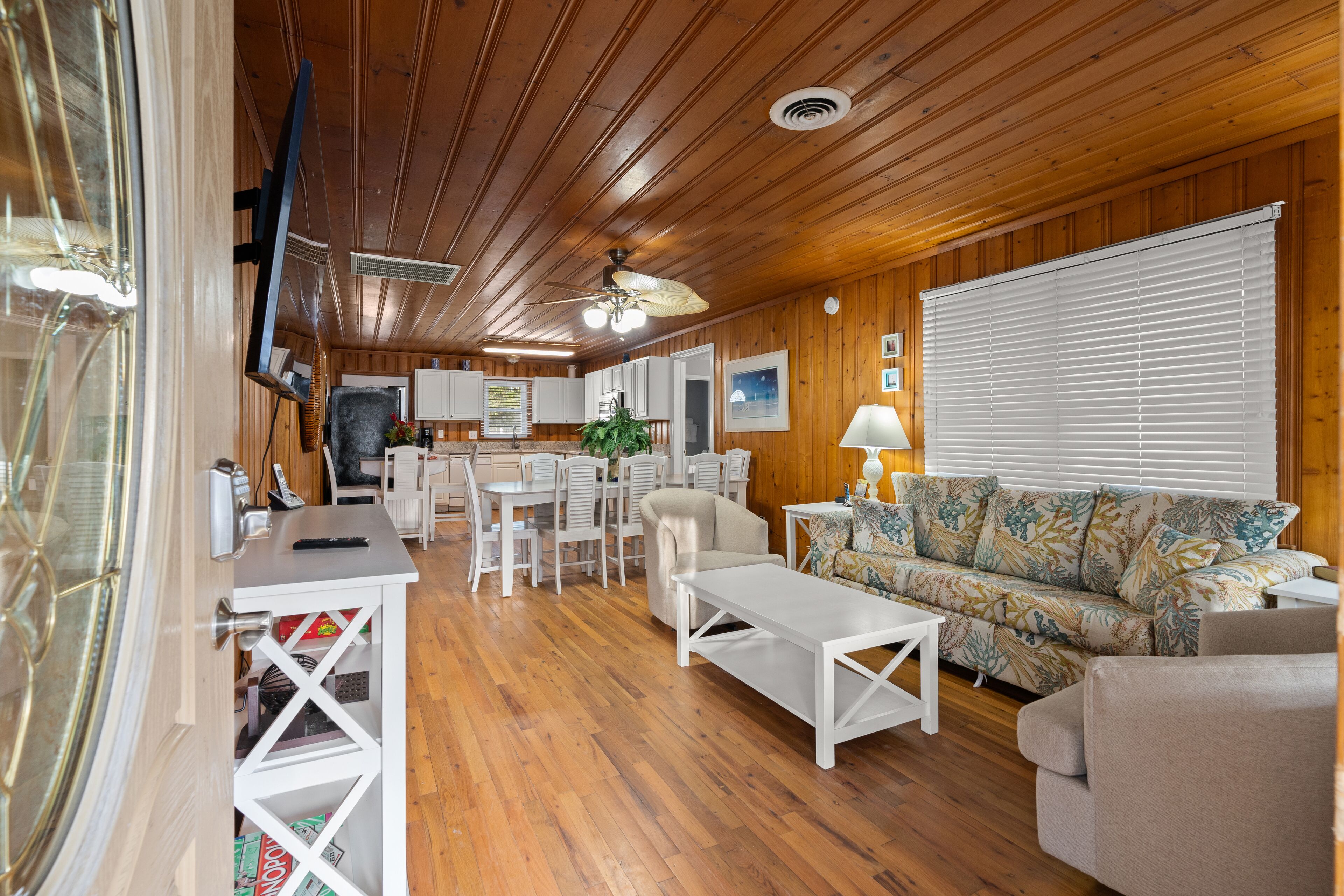 Un interior de cabaña acogedor con zona de comedor, sofá y televisor.