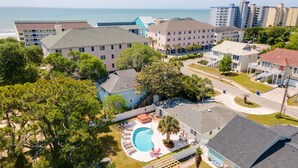 A residential area with a swimming pool, multiple-story buildings, and a view of the ocean.