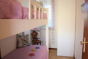 A room with bunk beds, a chair, and a door.