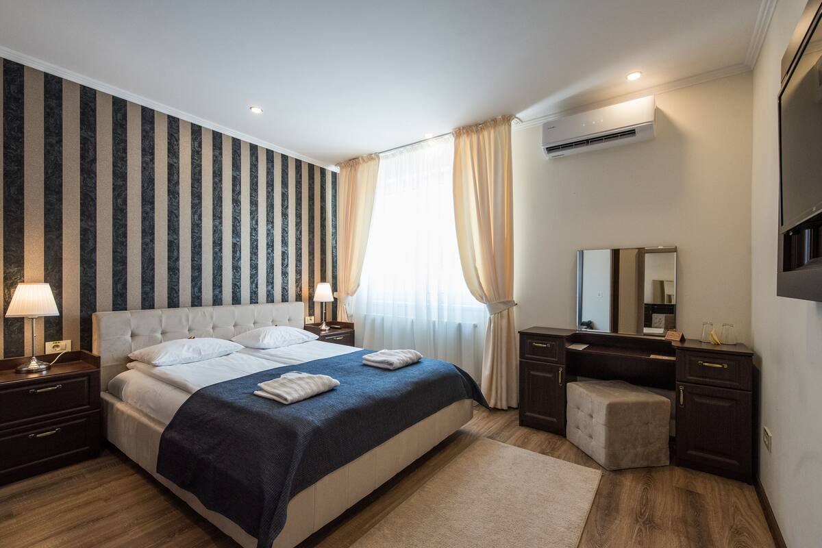 Une chambre d’hôtel moderne avec un grand lit, une coiffeuse avec un miroir et un bureau.