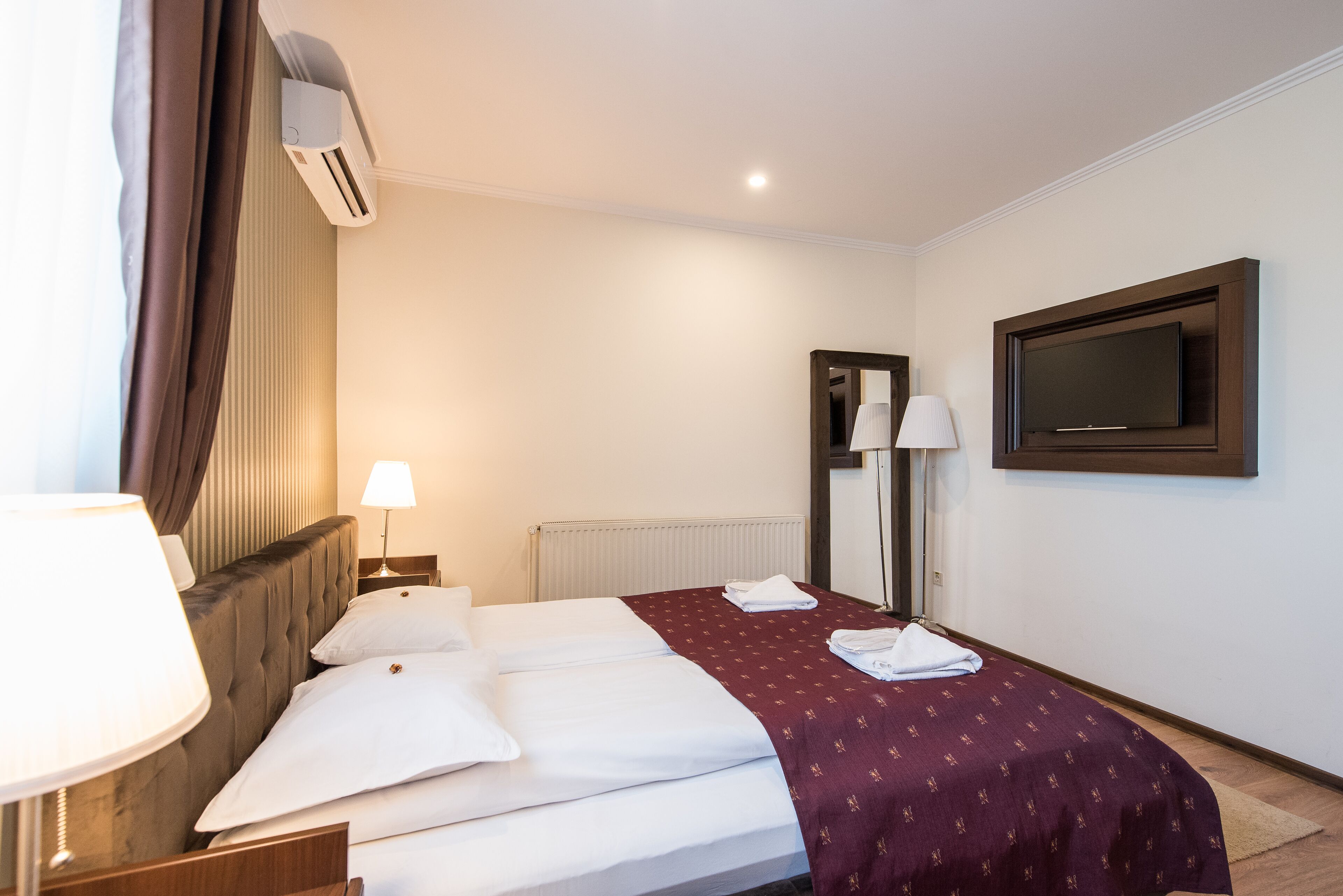 Habitación de hotel con cama, televisor de pantalla plana, lámpara y aire acondicionado.