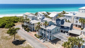 A coastal residential area with beachfront properties, including multi-story houses with balconies and a clear view of the ocean.