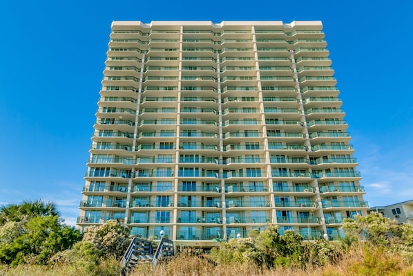 A multi-story hotel with a uniform exterior, balconies, and a clear sky.