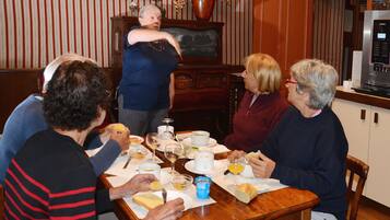 A group of people dining at a wooden table with various dishes and drinks.