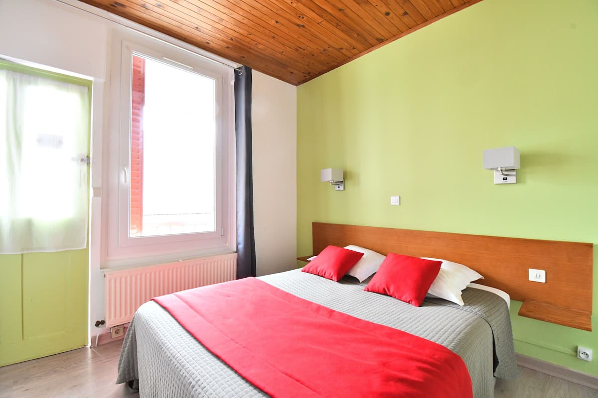 A bedroom with a bed, a window, and a door.