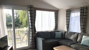 Una sala de estar moderna con un sofá seccional, una mesa de centro de madera y un  puerta corrediza de vidrio que da a un patio exterior.