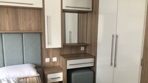 Un dormitorio pequeño con cama, un escritorio, un espejo y un armario.