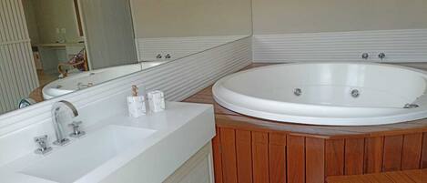 A bathroom with a large white bathtub, a sink, and a wooden vanity.