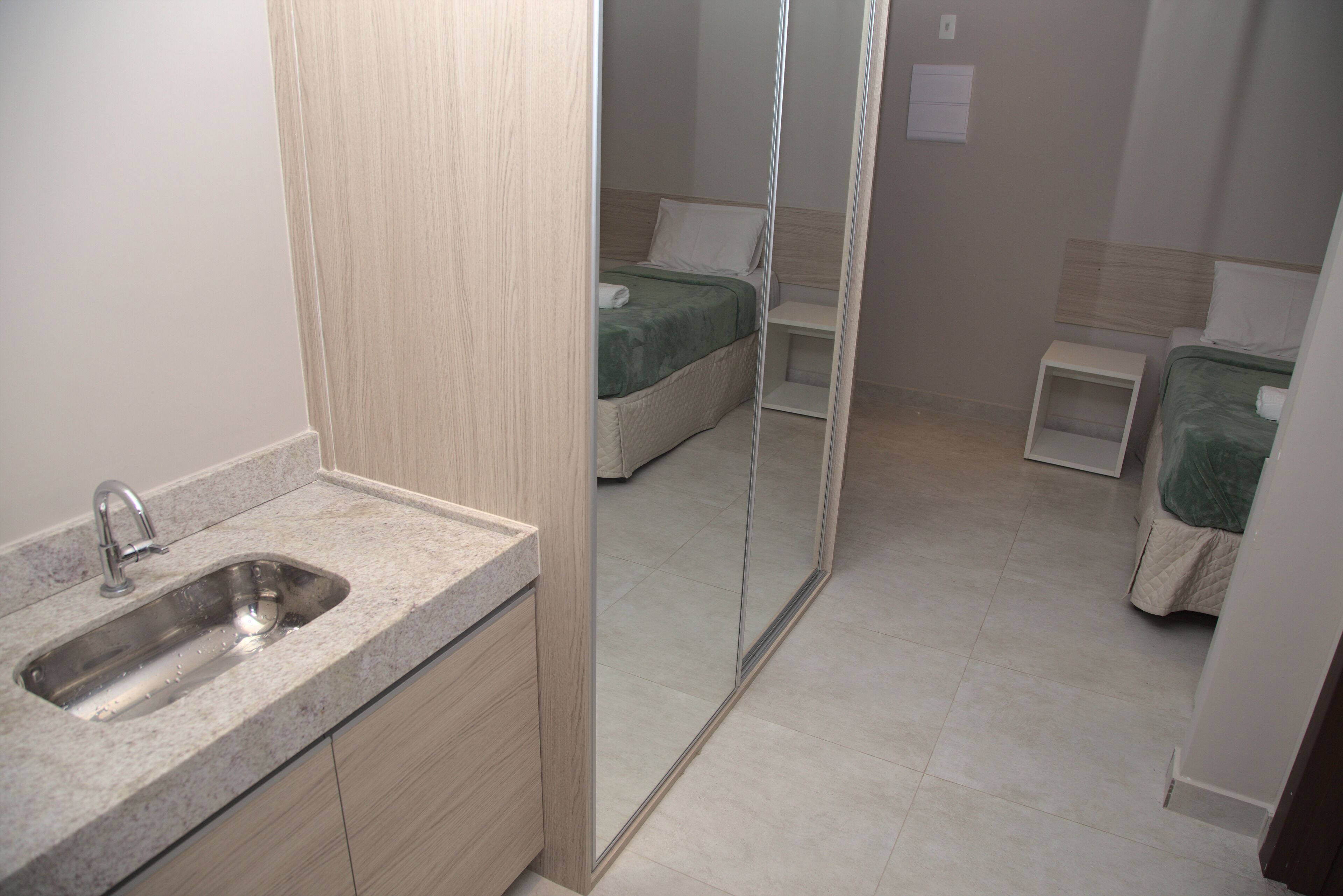 A modern bathroom with a granite countertop, a sink, and a mirror.