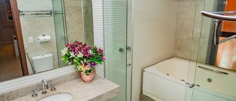 A modern bathroom with a glass-enclosed shower, a freestanding bathtub, and a granite countertop sink.