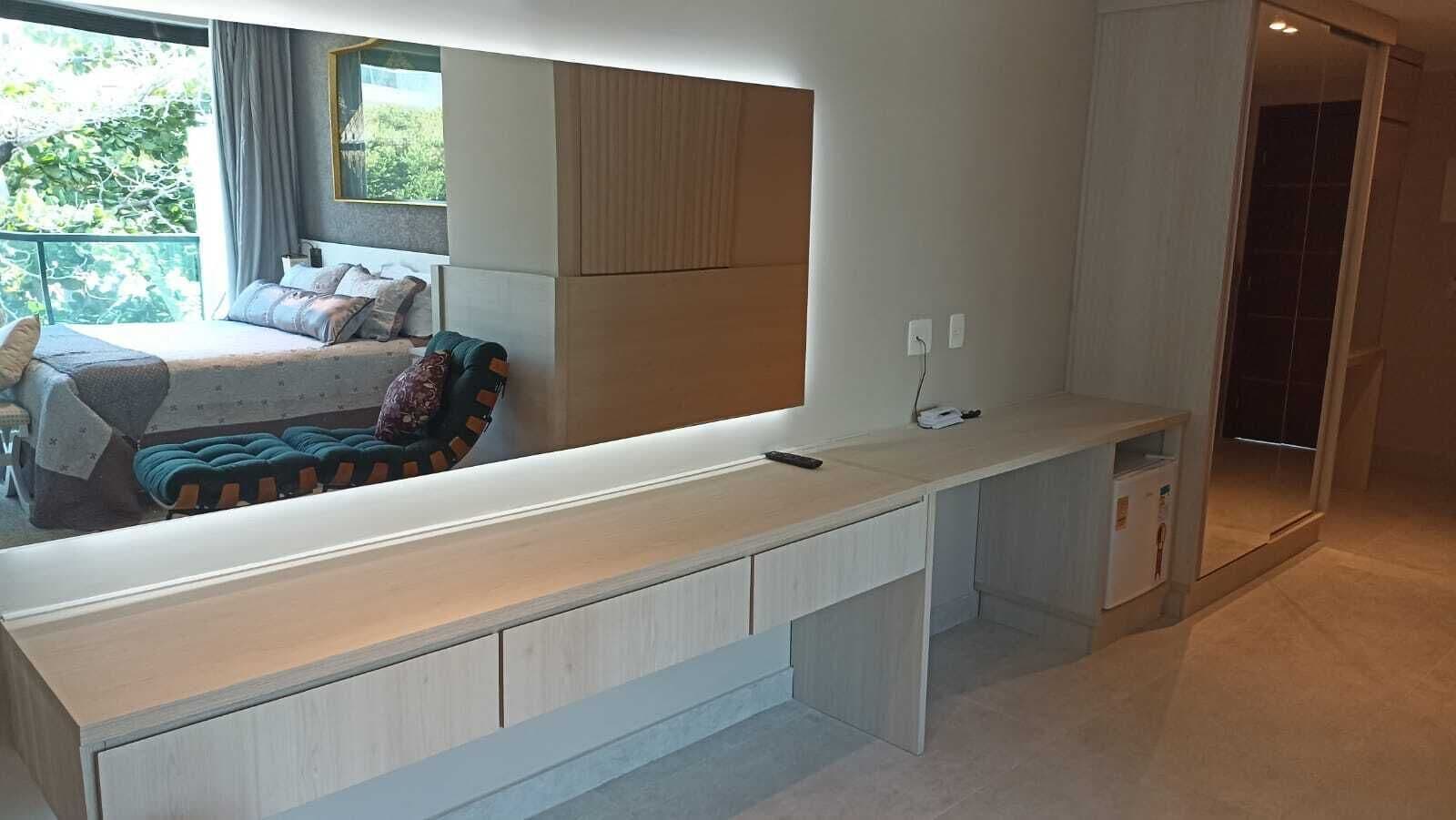 Un dormitorio moderno con un escritorio empotrado, una cama con cabecera estampada y vistas a zonas verdes.