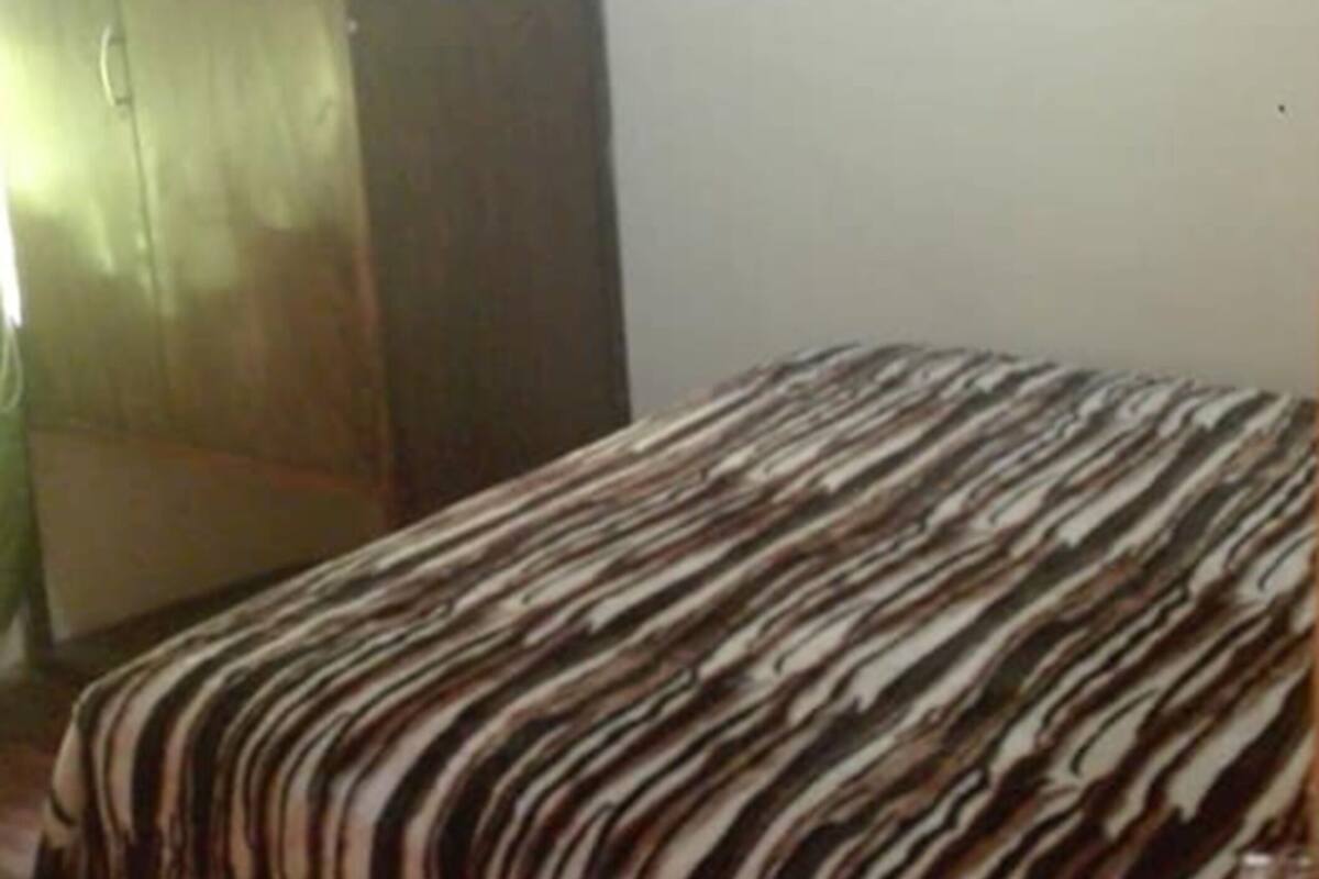 Une chambre à coucher avec un lit, une armoire et un téléviseur posé sur un meuble.