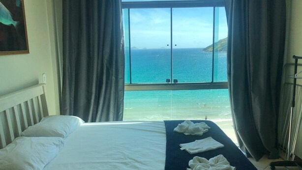 Ett hotellrum med ett stort fönster som erbjuder utsikt över havet och en strand.