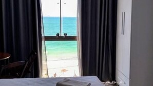 Ett hotellrum med en säng, en garderob och utsikt över havet.