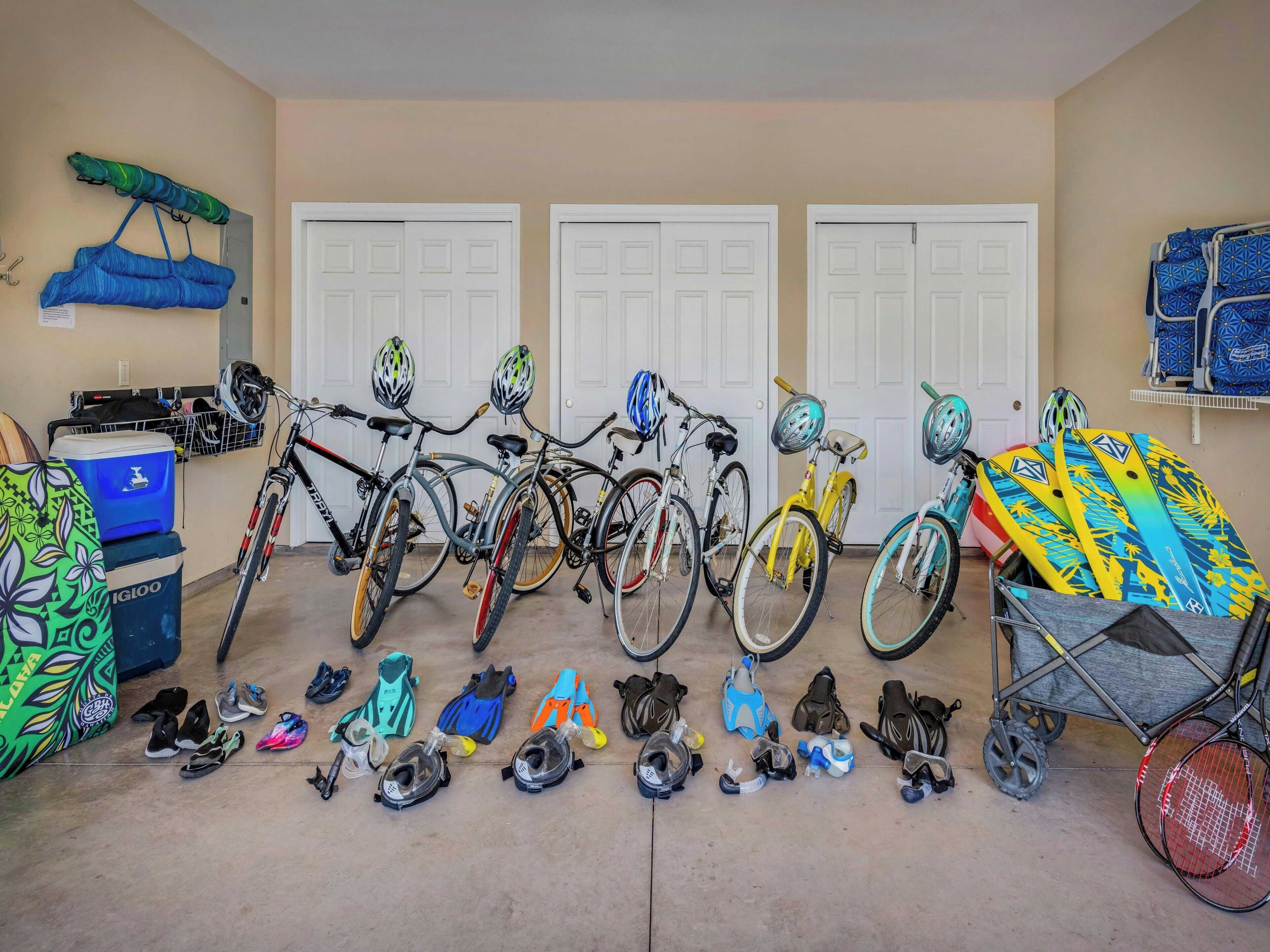 A garage with bicycles, helmets, and various sports equipment.
