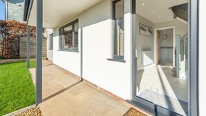 A modern house with a covered patio, large windows, and a visible kitchen area. - Seashells (2), Wells-next-the-Sea, Norfolk (Wells-next-the-Sea)