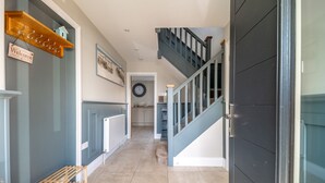 A hallway with a wooden bench, a welcome sign, a clock, and a staircase leading to another room. - Seashells (2), Wells-next-the-Sea, Norfolk (Wells-next-the-Sea)