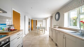 A modern kitchen with white cabinets, a wooden countertop, and a dining area with a table and chairs. - Seashells (2), Wells-next-the-Sea, Norfolk (Wells-next-the-Sea)