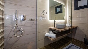 A modern bathroom with a glass-enclosed shower, a vanity with a sink, and a mirror. - Abaton Luxury Resort (Zakynthos)