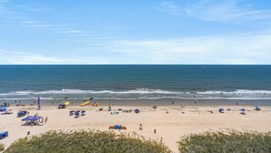 A beach with umbrellas, beach chairs, and a lifeguard tower. - San a bel 610, Lovely 2 BR Ocean Front Condo with an Indoor Swimming Pool and Ocean Front Hot Tub (NORTH MYRTLE BEACH)