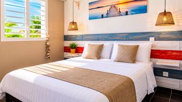 A bedroom with a bed, a wall-mounted shelf with a plant, a painting of a sunset, and a hanging light fixture.