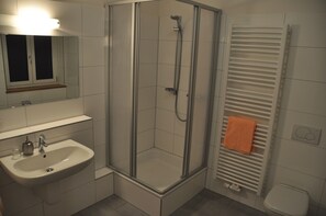 A bathroom with a glass-enclosed shower, a sink, and a toilet. - Hotel Lamm (Neckarsulm)