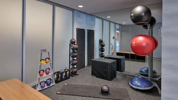 Une salle de sport équipée de matériel d’exercice, une table en bois et un miroir.
