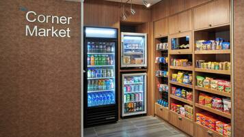 Un mercado de barrio con dispensadores refrigerados para bebidas y estantes llenos de aperitivos y bebidas.