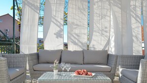 A sunlit outdoor seating area with wicker furniture, a glass table, and a plate of grapes. - House Diamond, Okrug Gornji - ideal for relaxing holidays for families & friends (Okrug Gornji)