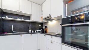 A modern kitchen with white cabinets, a black countertop, and a built-in oven. - House Diamond, Okrug Gornji - ideal for relaxing holidays for families & friends (Okrug Gornji)