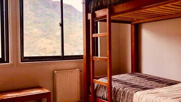 A bunk bed room with a window overlooking a mountainous landscape.