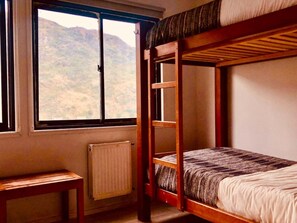A bunk bed room with a window overlooking a mountainous landscape. - Refugio Vértice Paine Grande Hostel (Torres del Paine)