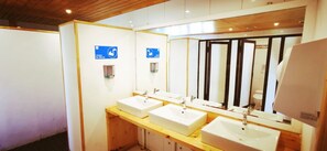 A modern bathroom with three sinks, wooden vanity, and a large mirror. - Refugio Vértice Paine Grande Hostel (Torres del Paine)