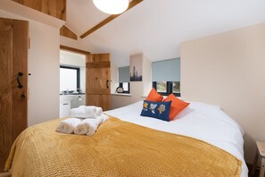 A bedroom with a bed, a wooden wardrobe, a bathroom, and a window with a view.