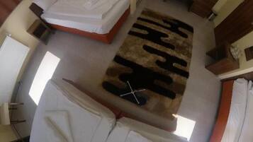 Una habitación con cama, una mesita, una silla y una ventana.