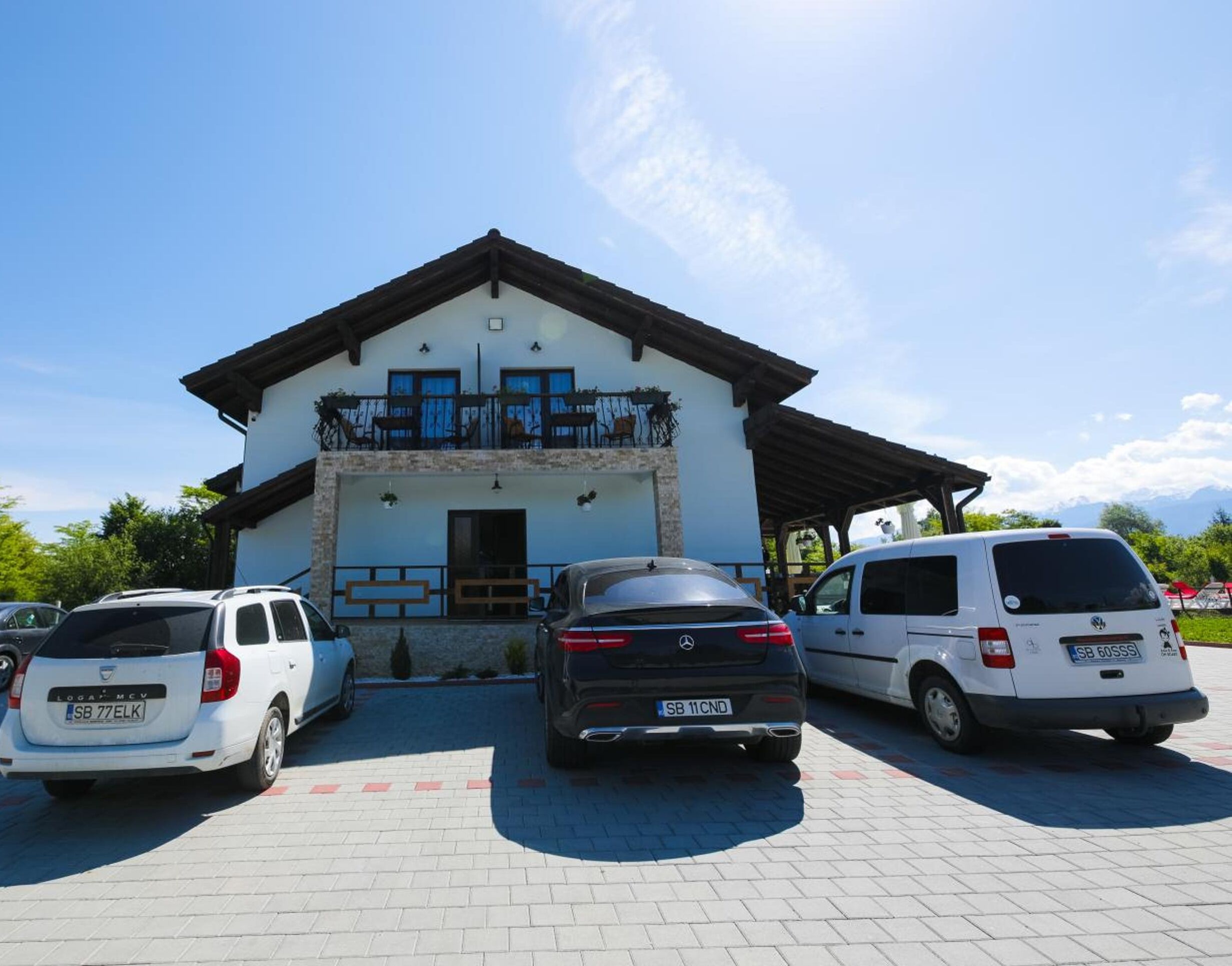 A building with a covered patio and three parked cars.