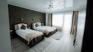 A hotel room with two beds, a large window with curtains, a modern chandelier, and a patterned rug. - Popasul Montan (Avrig)