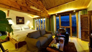 A cozy room with a bed, a sofa, a coffee table with a vase, and large windows with curtains. - Lijiang Seven Island Resort (Lijiang)
