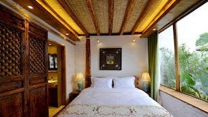 A bedroom with a large bed, wooden wardrobe, and a window with a view of greenery. - Lijiang Seven Island Resort (Lijiang)