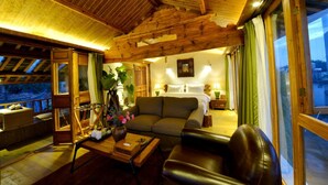 A cozy room with a wooden ceiling, a bed, a sofa, and a table with a vase of flowers. - Lijiang Seven Island Resort (Lijiang)