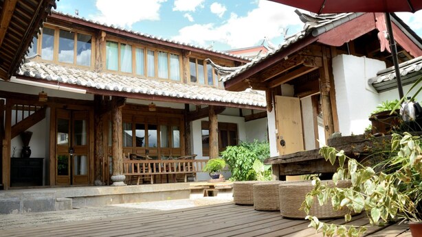 A traditional wooden building with a tiled roof and a wooden deck. - Lijiang Seven Island Resort (Lijiang)
