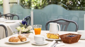 A breakfast table with croissants, a cup of coffee, a glass of orange juice, a basket, and a pitcher. - Hotel Garden Riccione (Riccione)