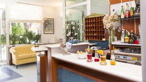 A modern kitchen with a bar area, a yellow sofa, and a large window with a view of greenery. - Hotel Garden Riccione (Riccione)