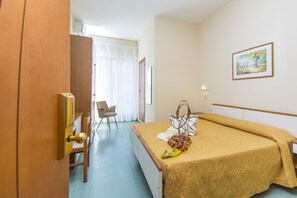A hotel room with a bed, a chair, a door, and a painting on the wall. - Hotel Garden Riccione (Riccione)