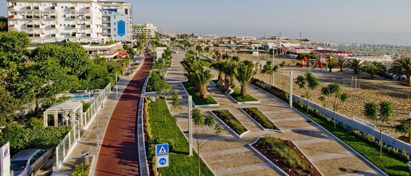 A coastal urban area with a paved walkway, greenery, and a large building with balconies. - Hotel Garden Riccione (Riccione)