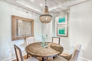 Uma sala de jantar com uma mesa redonda de madeira, quatro cadeiras e um lustre de cristal.