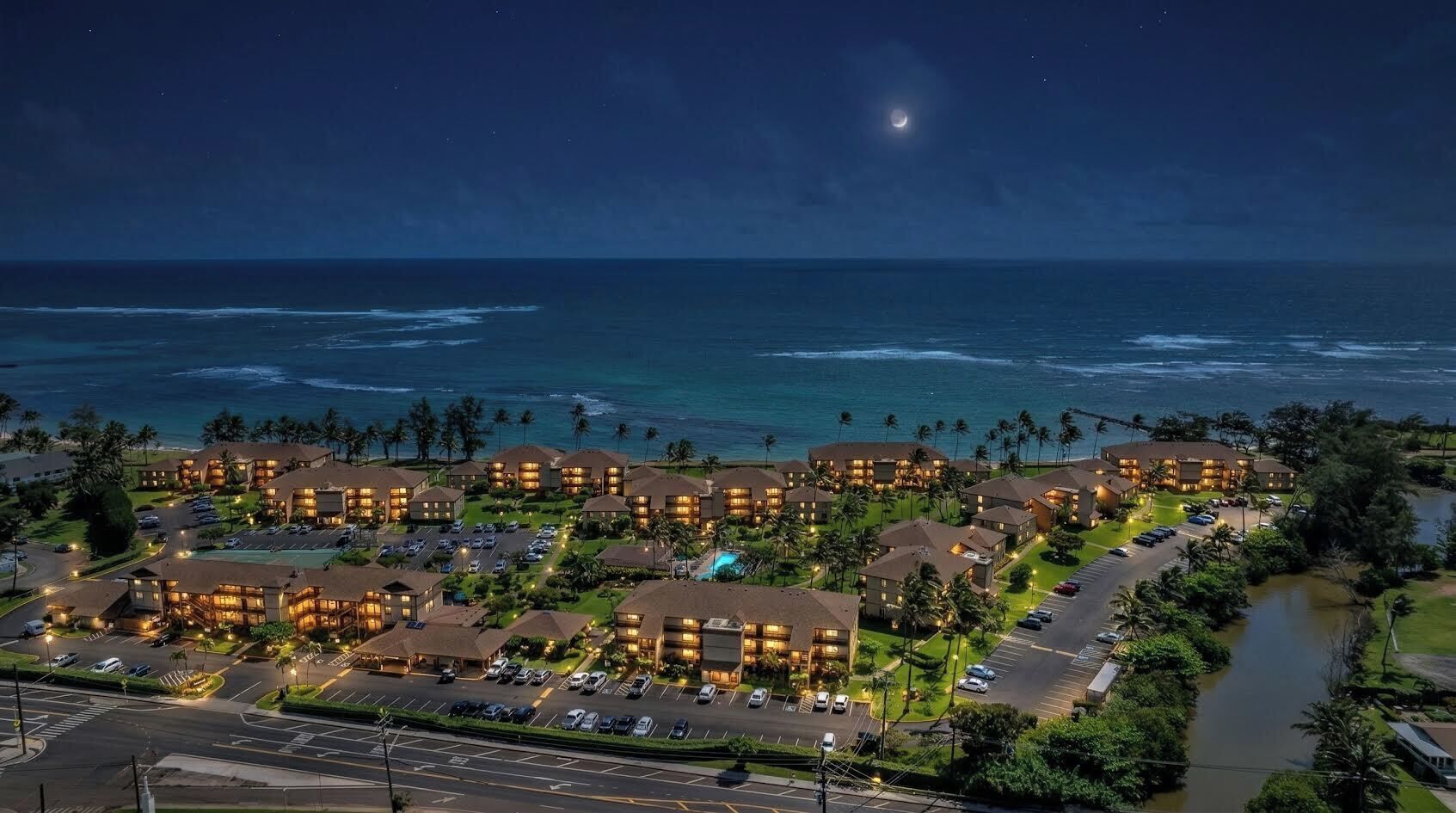 Un resort con varias edificaciones, un estacionamiento y vista al océano.