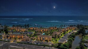 A resort with multiple buildings, a parking area, and a view of the ocean.